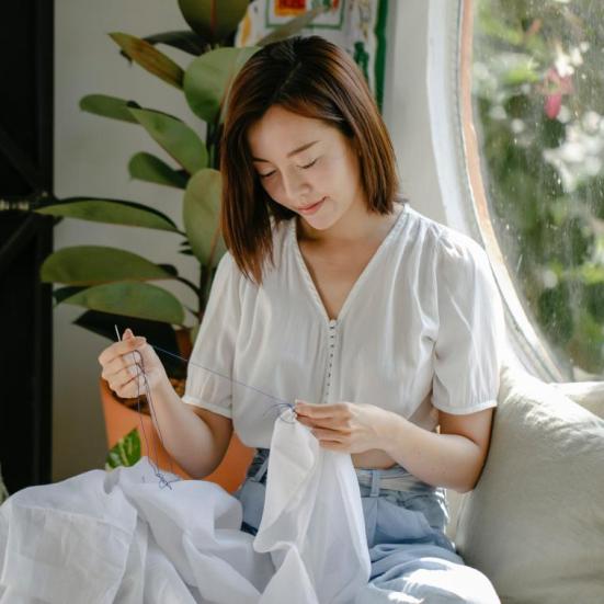 Kvinde med sytøj. Bøger om kreativt genbrug og reparation. 