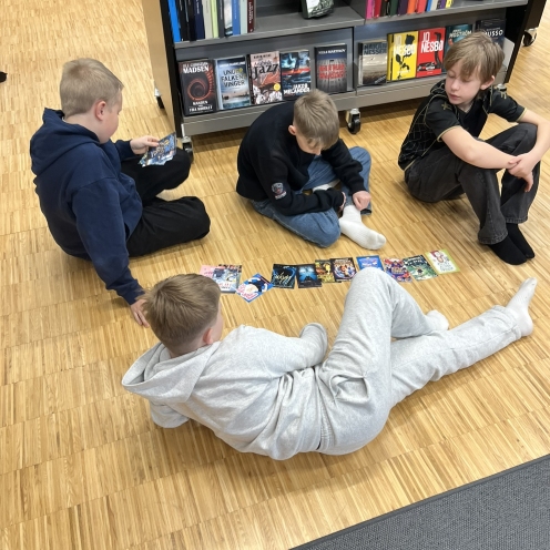 Fire drenge, der sidder på gulvet og kigger på bogforsider